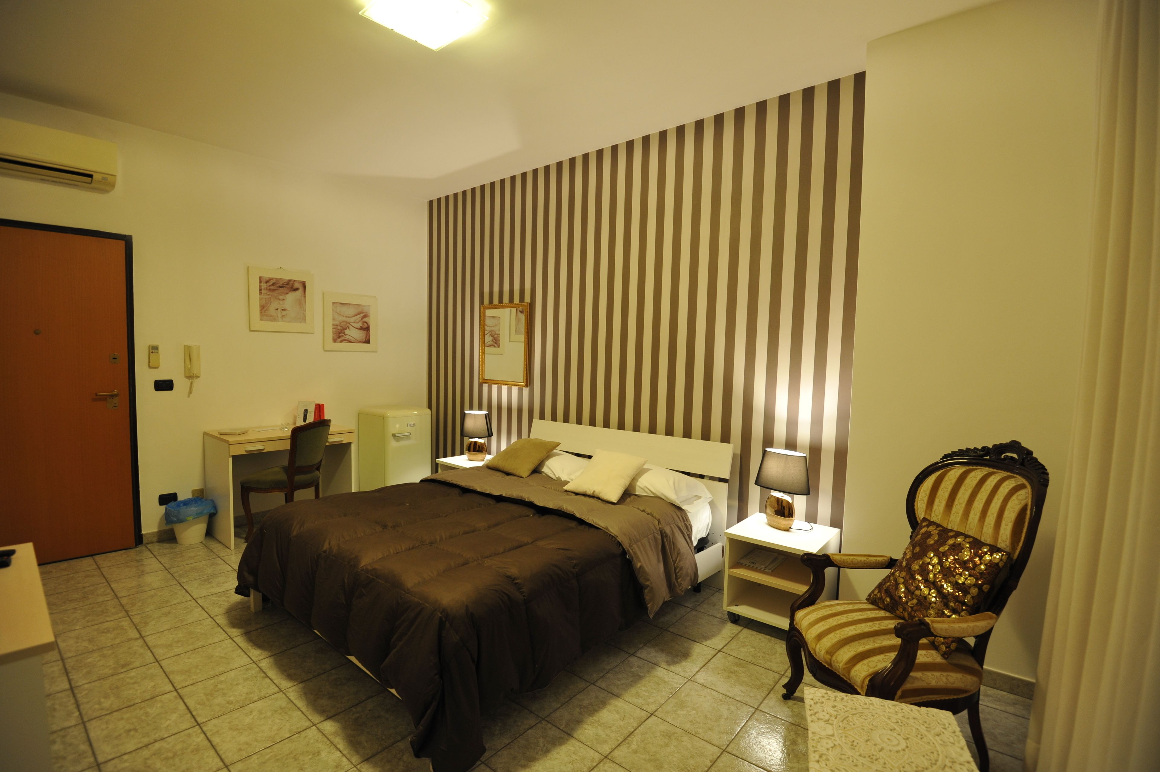 A hotel room with a bed, a desk, a chair, and a nightstand.