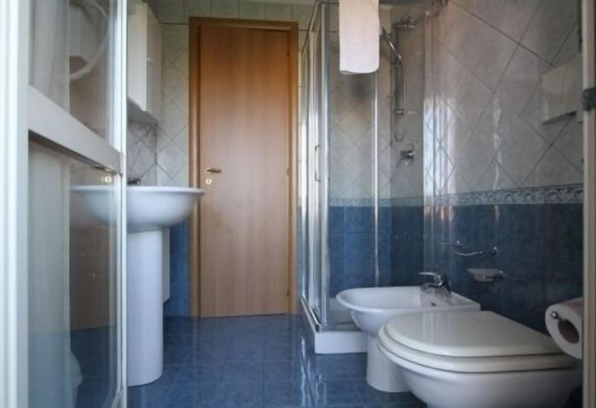 A bathroom with a shower, two toilets, and a sink.