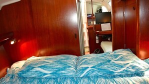 Un dormitorio con cama, paredes de madera y una televisión al fondo.