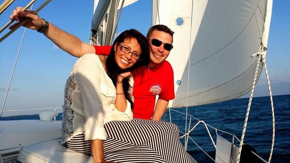 A sailboat with a person in a red shirt and another in a white shirt.