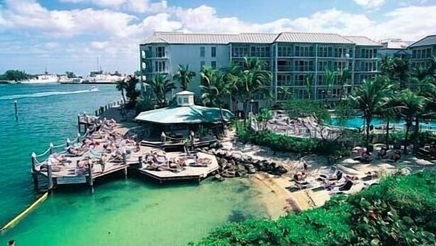 Un resort con un edificio grande, una piscina y un muelle con barcos.