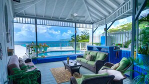A covered outdoor area with a pool, seating, and a view of the ocean. - The Lighthouse Villas (Cane Garden Bay)
