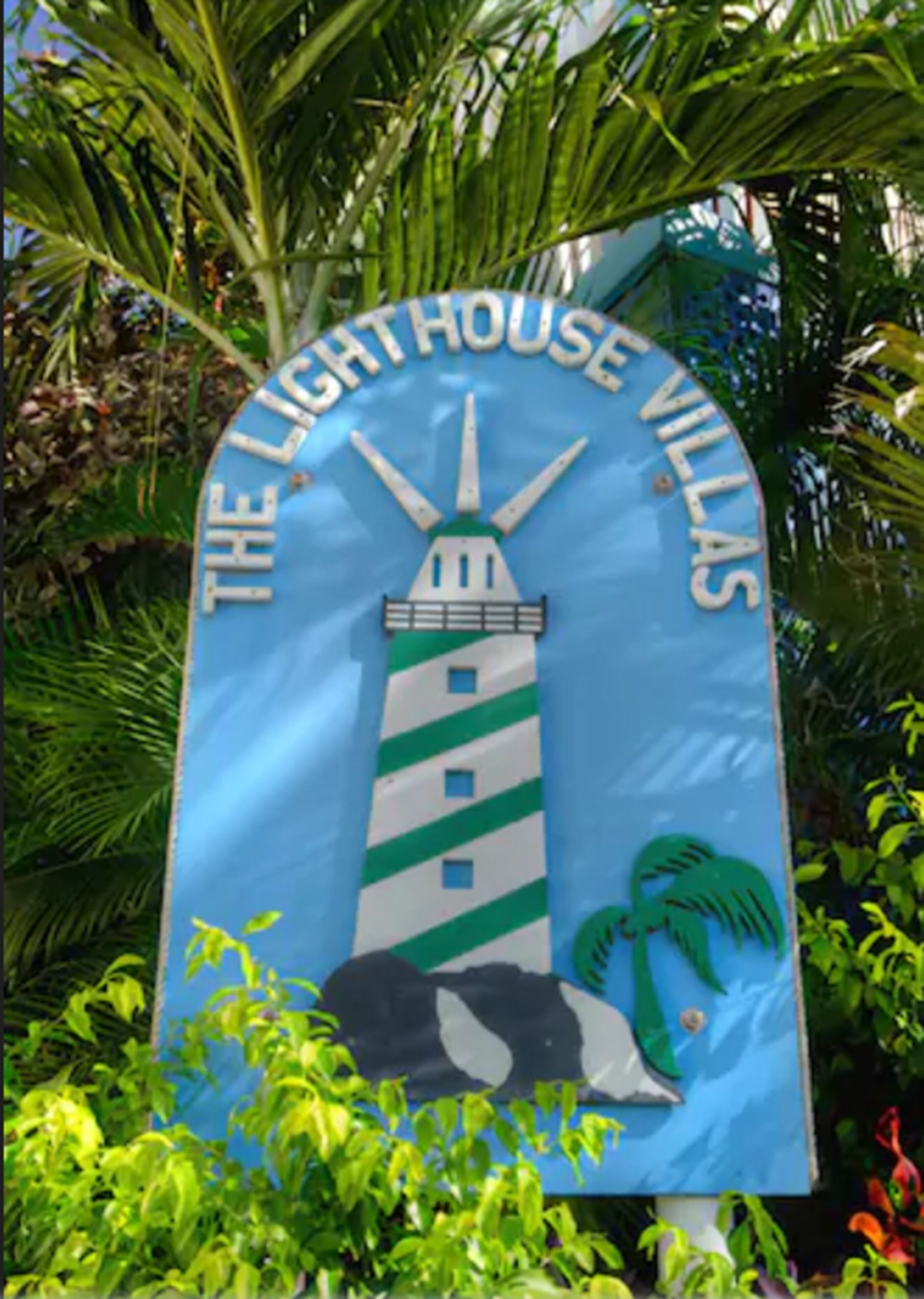 Placa de The Lighthouse Villas com ilustração de farol e palmeiras.
