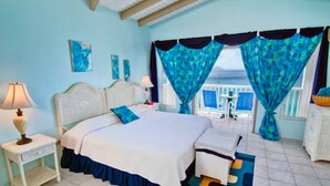 A bedroom with a bed, nightstand, and a view of the sea. - The Lighthouse Villas (Cane Garden Bay)