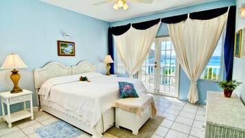 A bedroom with a bed, bedside tables, a bench, curtains, and a view of the outdoors.