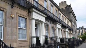 A row of traditional terraced houses with black iron gates and a narrow sidewalk. - Windsor Street Apartments (Edinburgh)