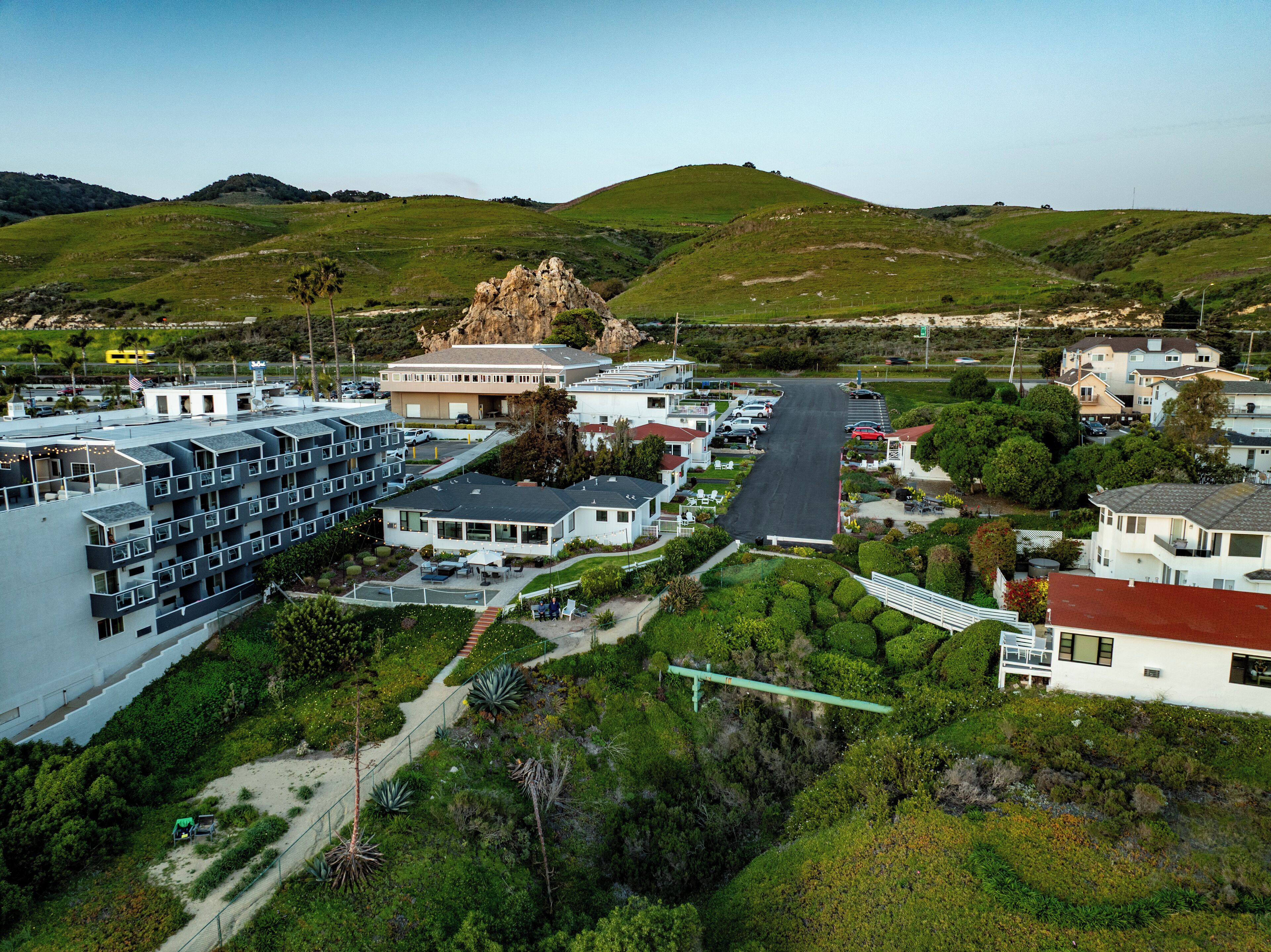 Zona residencial com uma formação rochosa notável, edifícios de apartamentos modernos e uma estrada bem cuidada.