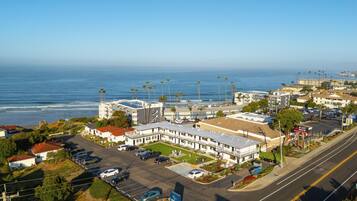 A coastal hotel with a parking lot, a view of the ocean, and a sign for 'BLAST BREW'.