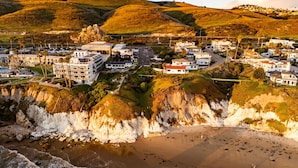 Eine Küstenstadt mit Wohnhäusern, einem Strand und Hügeln im Hintergrund.