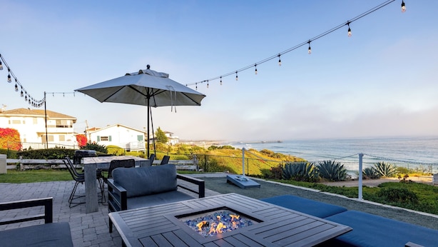 Eine Terrasse im Freien mit Feuerstelle, Sitzgelegenheiten und Lichterkette.