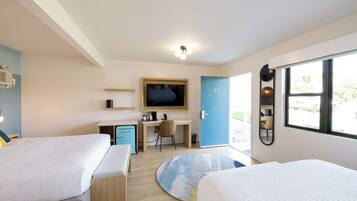 Una habitación de hotel moderna con dos camas, un escritorio, un televisor y un ventanal grande.