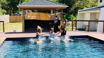 Relax by the pool surrounded by a covered seating area and a wooden deck.