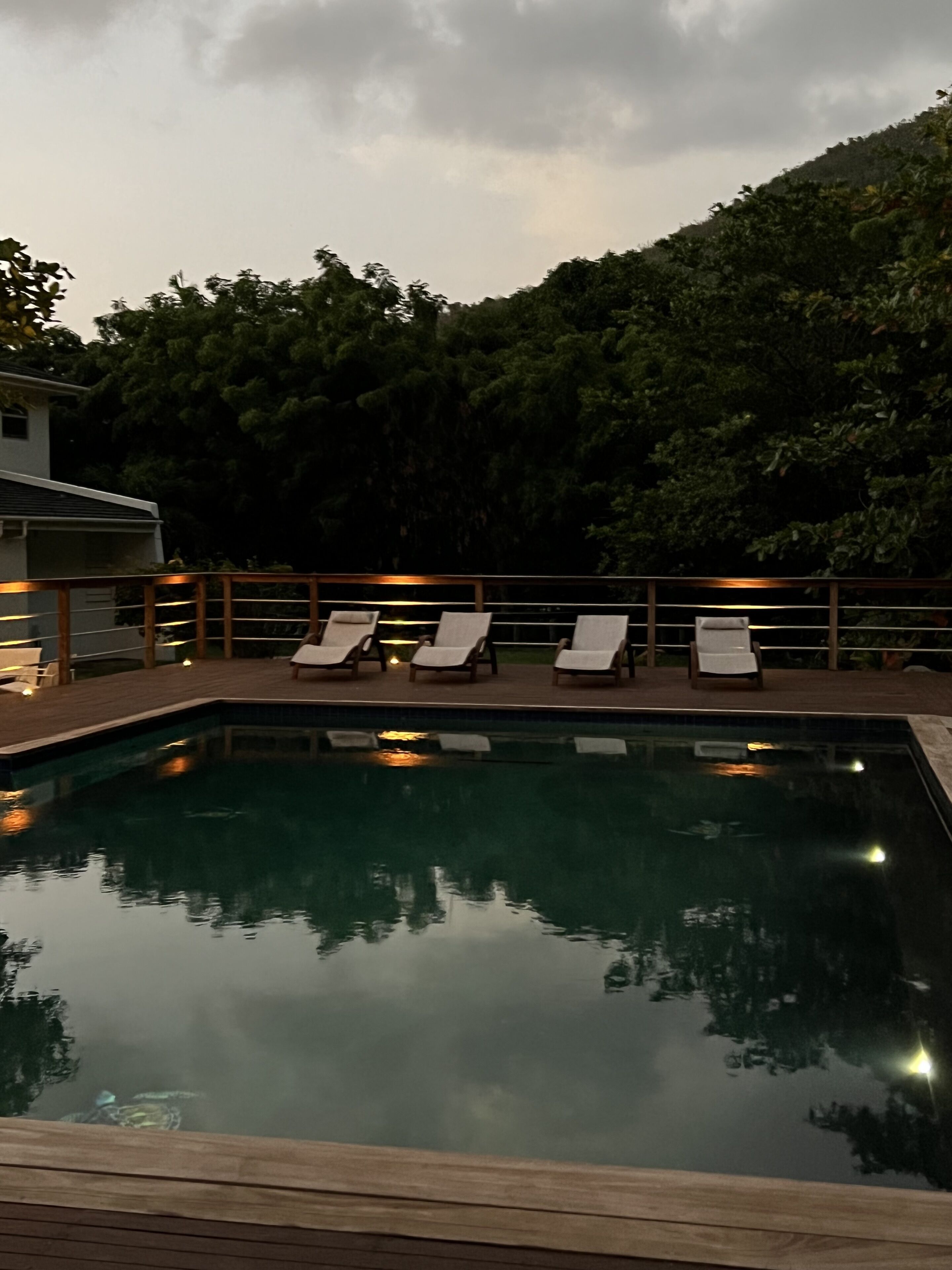 A swimming pool with lounge chairs and a wooden deck.