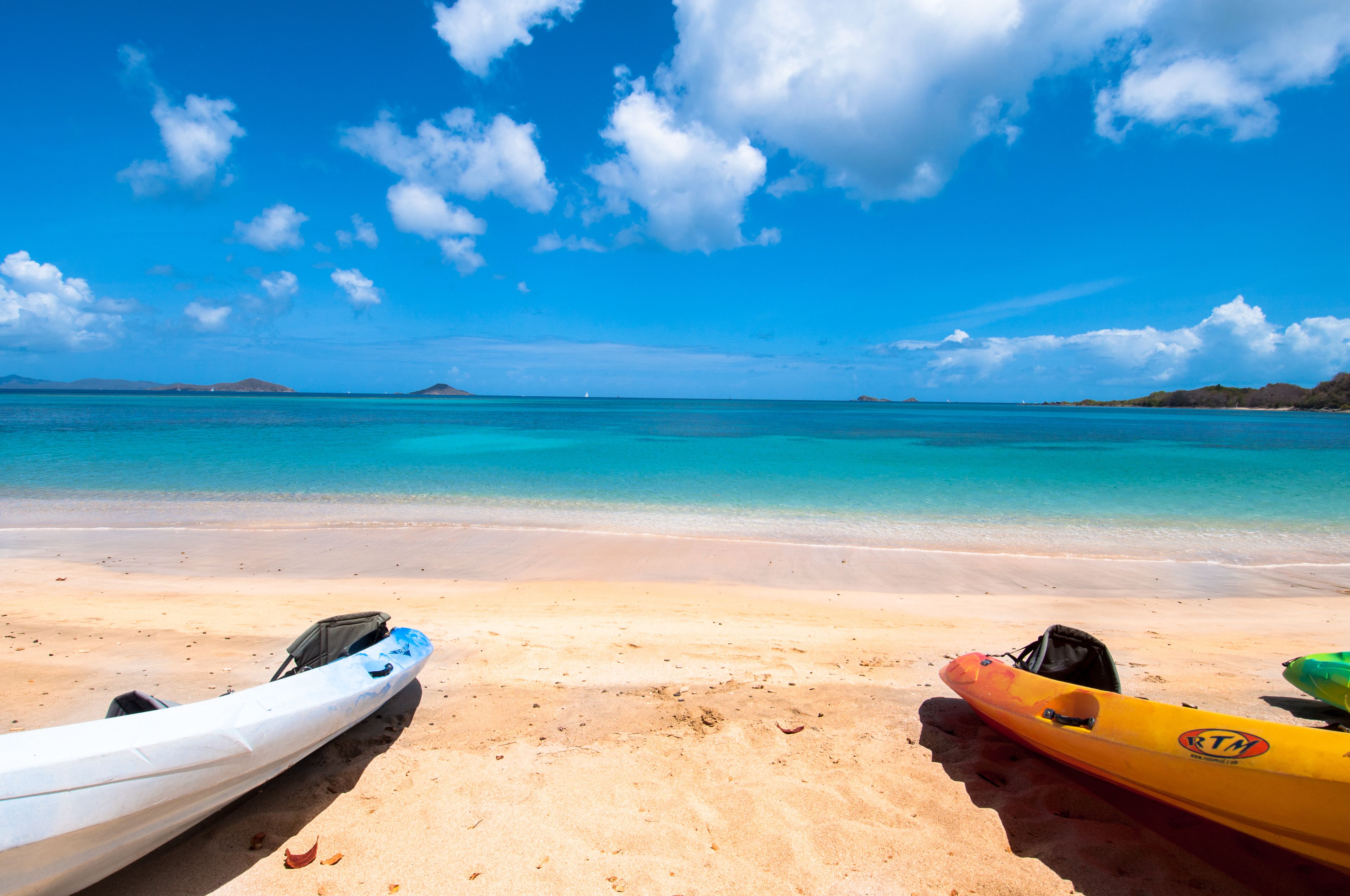 A beach with kayaks and a clear blue sky.