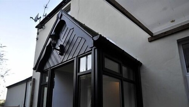 Un coin d’un bâtiment avec un cadre de fenêtre noir et un mur blanc.