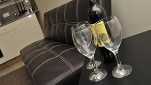 Un canapé en cuir marron foncé, avec une bouteille de vin et deux verres posés sur une table.