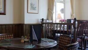 Un comedor con una mesa redonda, sillas y una ventana con cortinas.
