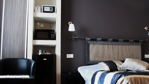 Une chambre avec un lit, un bureau, une chaise, un four à micro-ondes et une table de chevet.