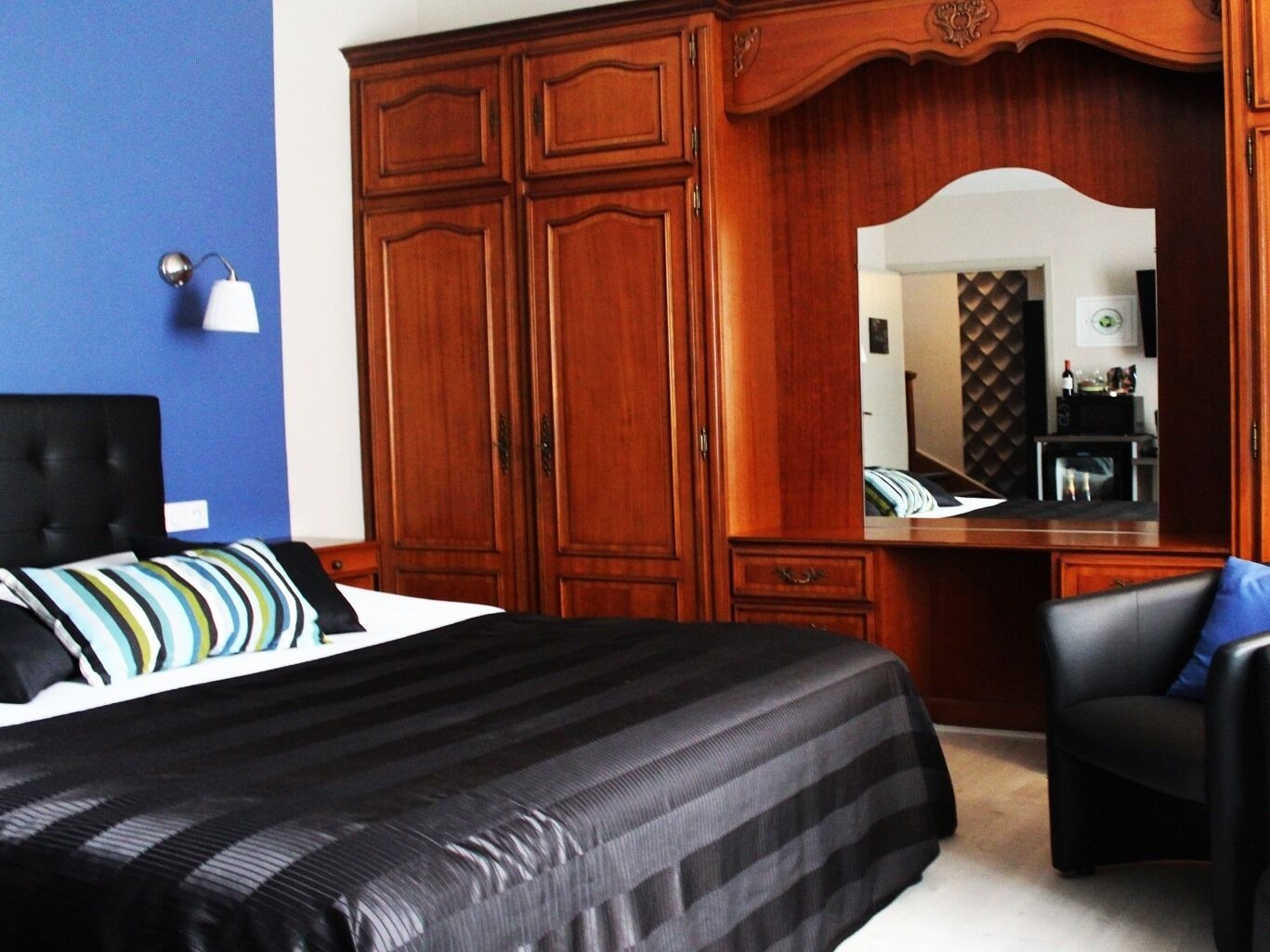 A bedroom with a bed, a dresser, a chair, and a mirror.