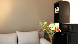 Un salon avec un canapé gris, un meuble noir et un vase rempli de fleurs.