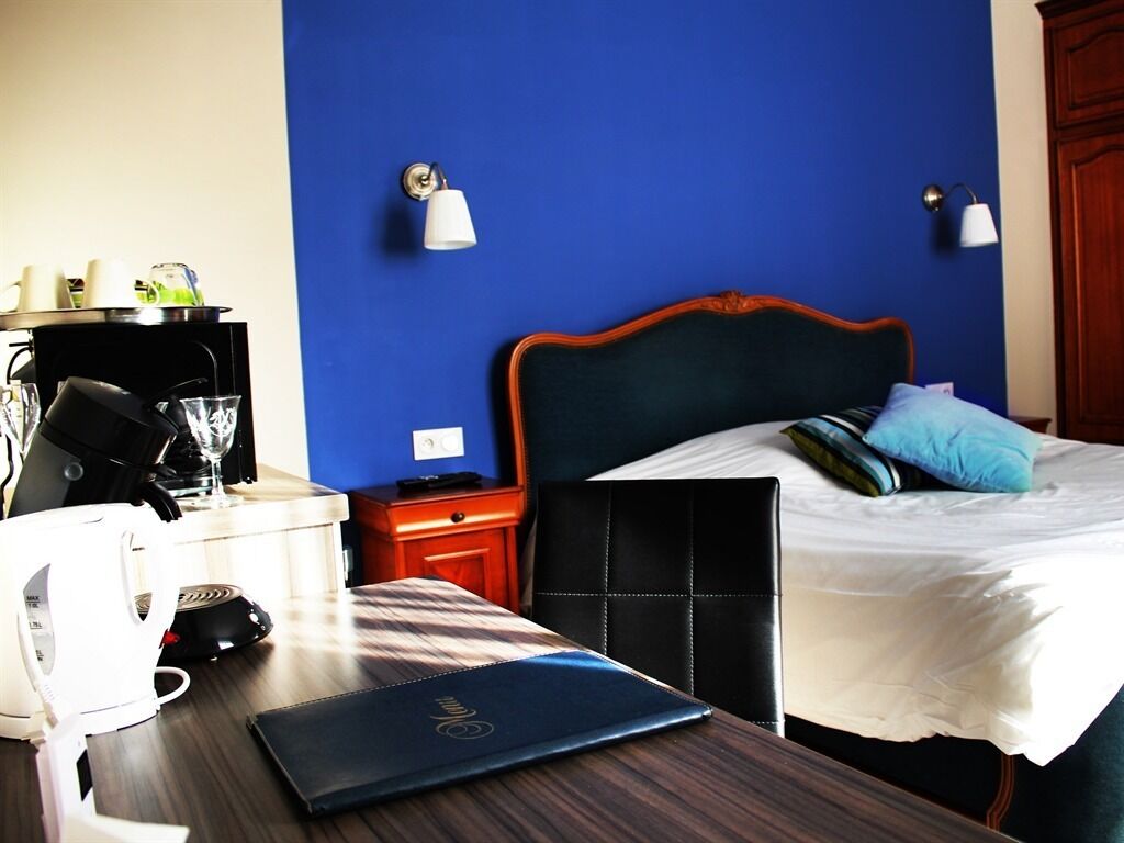 A hotel room with a bed, bedside table, and a desk with a laptop and coffee maker.