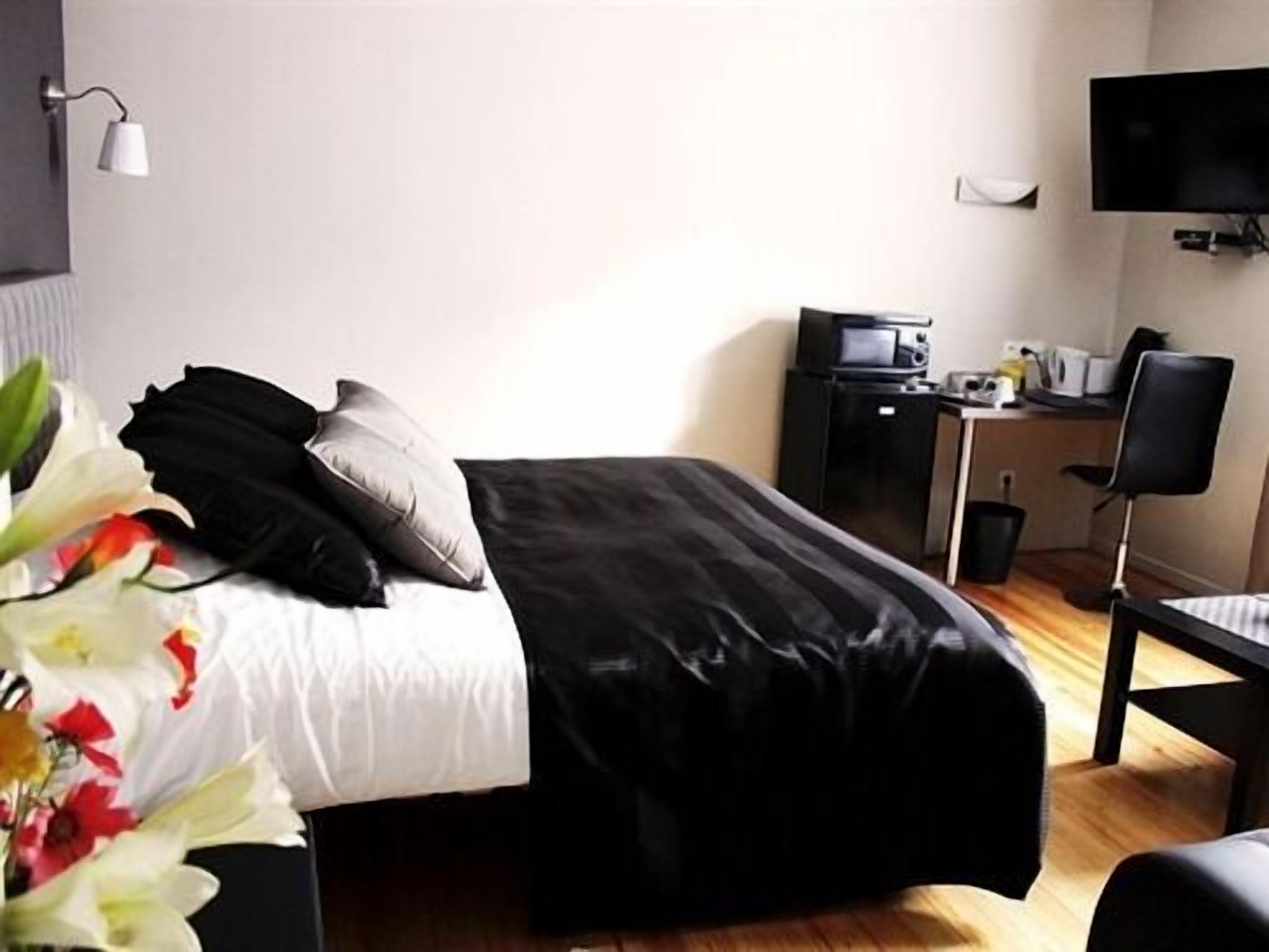 A hotel room with a bed, a desk with a computer, a chair, and a TV.