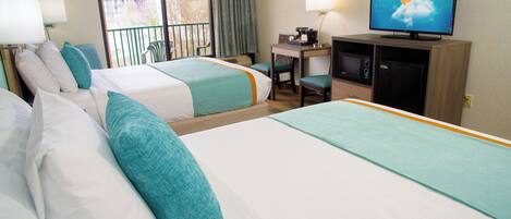 A hotel room with two beds, a desk, a television, and a balcony.