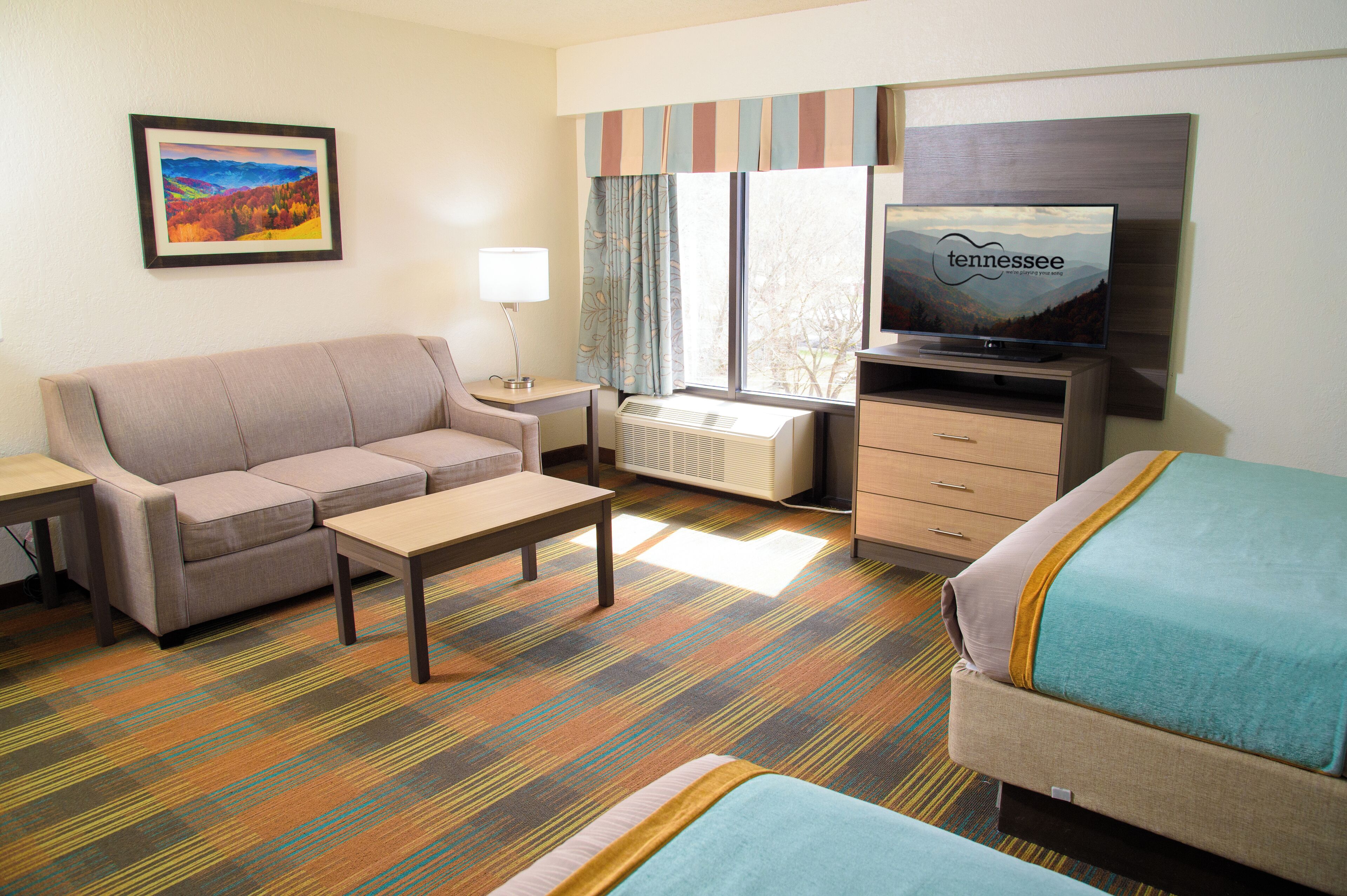 Una habitación de hotel con sofá, televisión, escritorio y cama.