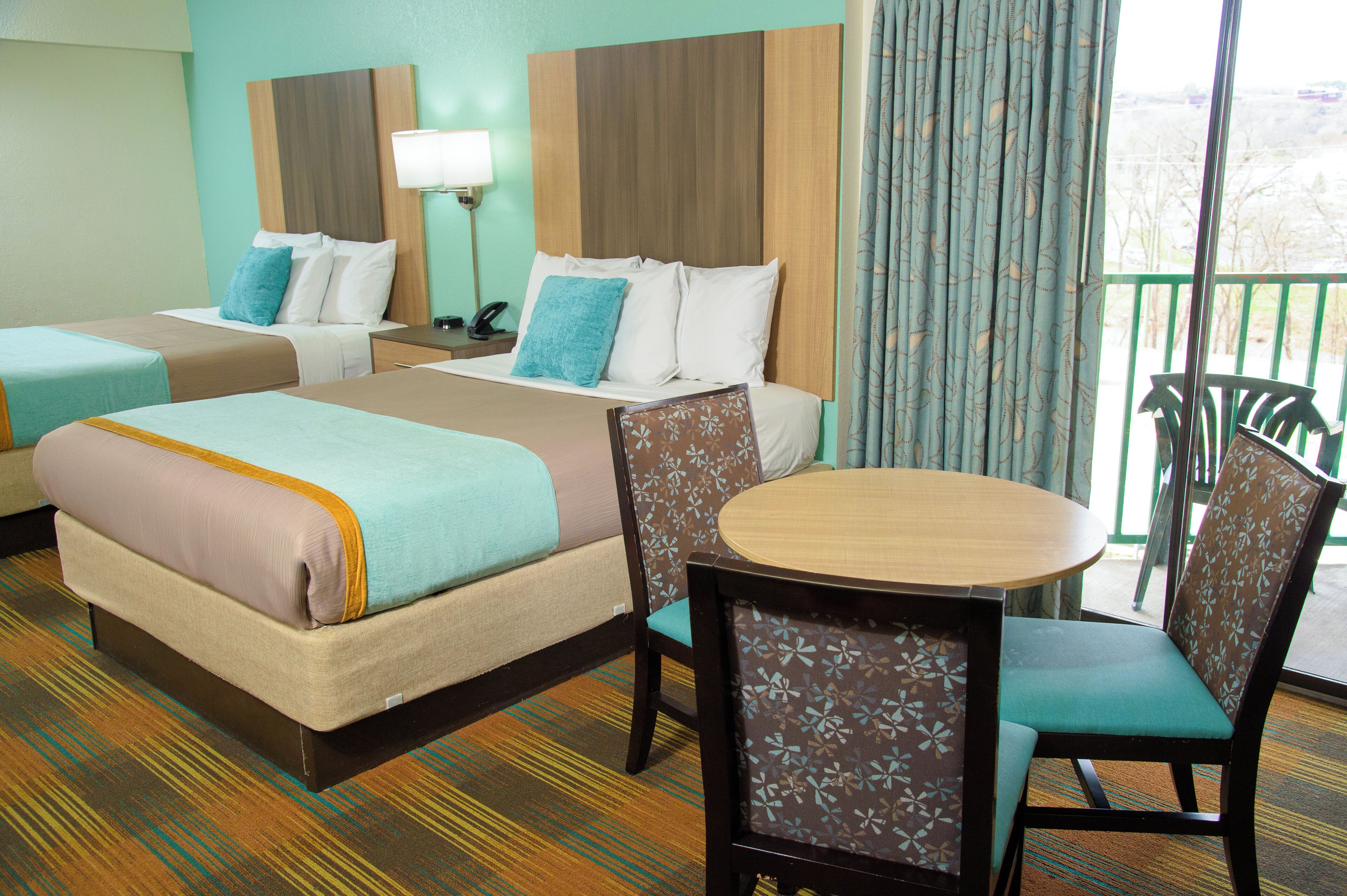 A hotel room with two beds, a small table, and chairs.