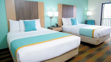 Habitació d'hotel amb dos llits, cadascun amb roba de llit blanca i verd mar, amb capçaleres de fusta i làmpades a sobre del llit.
