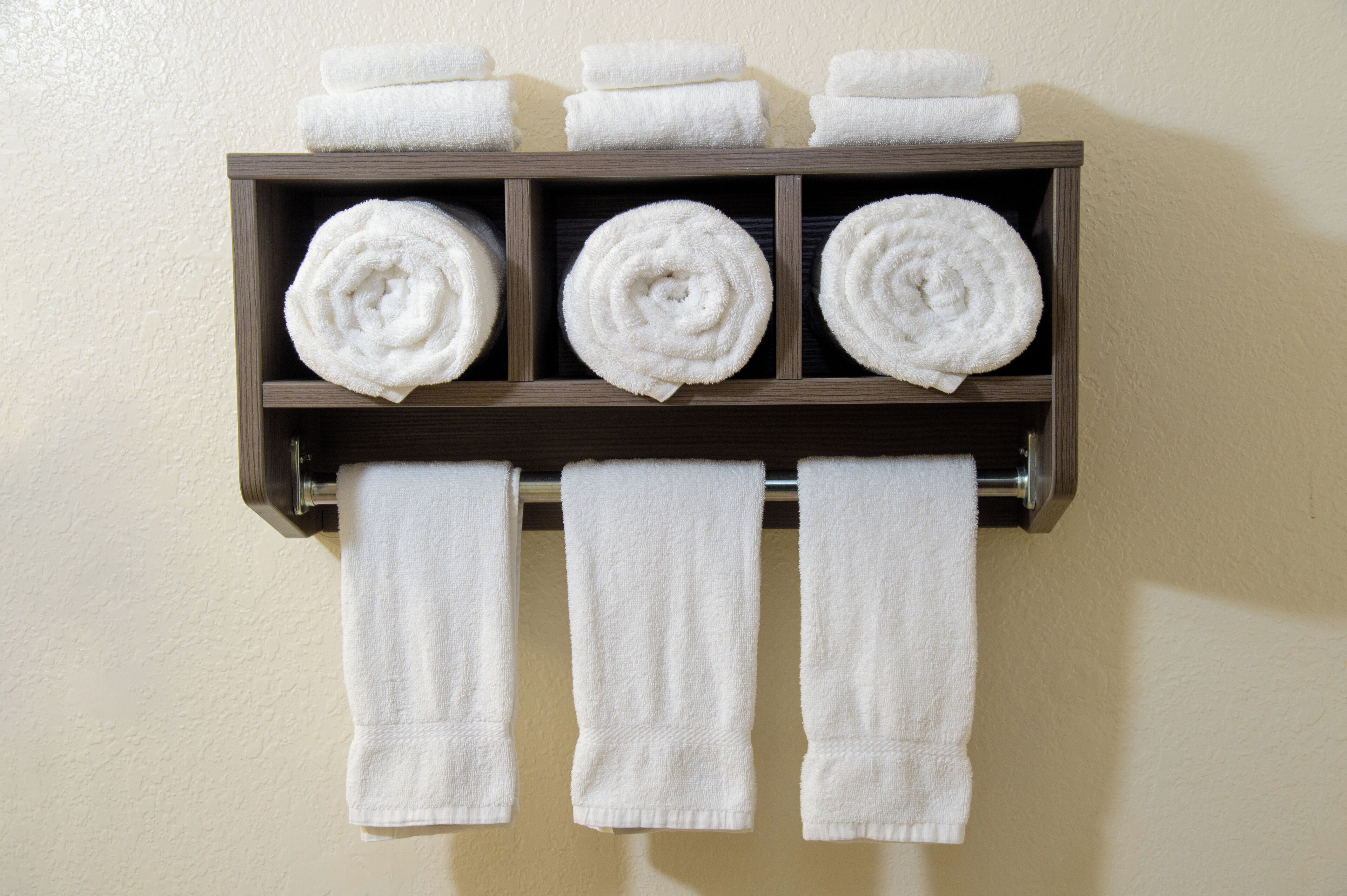 A towel rack with six neatly rolled towels and three hanging towels.