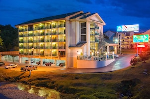A multi-story hotel with balconies, a parking area, and a visible sign for the Pigeon River Inn.