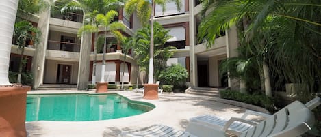 A pool area with lounge chairs and palm trees.