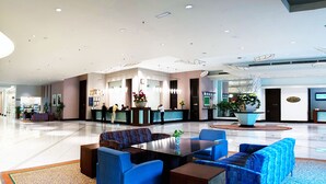 Un vestíbulo espacioso con mostrador de recepción, zona de estar y un gran jarrón decorativo.