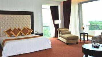 Una habitación de hotel con una cama grande, un sofá, una silla y una mesita.