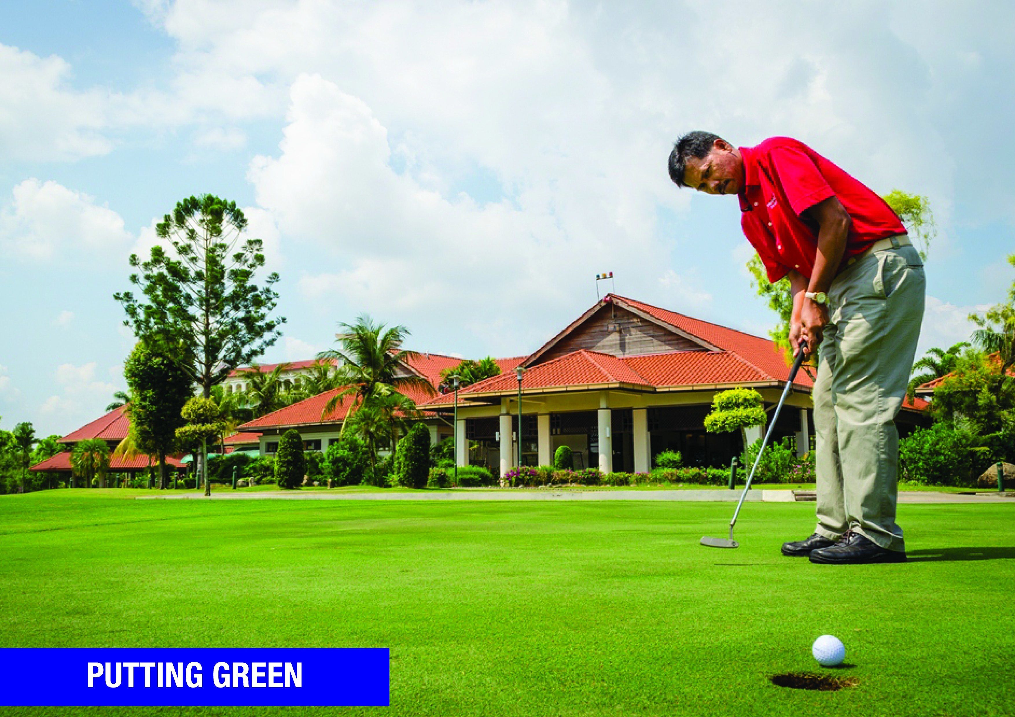 A golf course with a red-roofed building in the background.