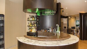 Un área de bar moderna con una barra curva, estantes llenos de botellas y una luz de neón verde.