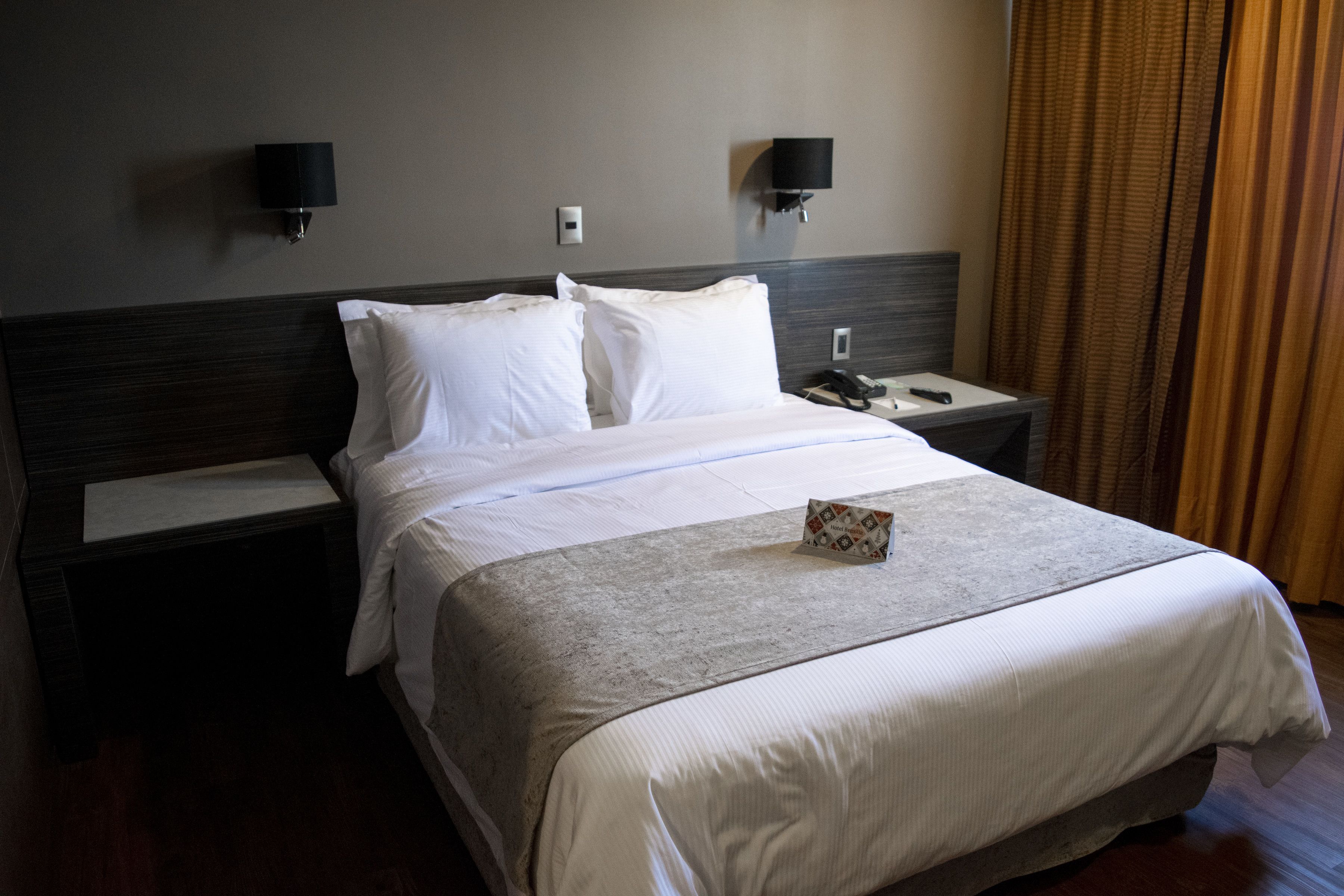 Ein Hotelzimmer mit einem großen Bett, zwei Nachttischen, einer Ablage und einer Wandleuchte.