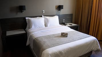 Ein Hotelzimmer mit einem großen Bett, zwei Nachttischen, einer Ablage und einer Wandleuchte.