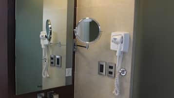 Un baño moderno con un lavamanos rectangular, un espejo, un secador de pelo y un dispensador de toallas.