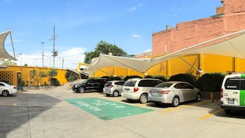 Un estacionamiento con varios automóviles y un letrero de accesibilidad verde.