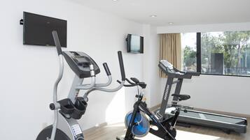 Un gimnasio con una máquina elíptica, una bicicleta estática y una cinta de correr.