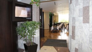 Interior moderno de restaurante con área de recepción, una planta en maceta y un cartel que indica el nombre 'Copacabana Restaurante - Bar'.