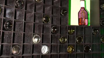 A wall with a grid of square panels, some containing clear glass bottles.