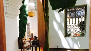A tranquil indoor water feature with a tiled floor, a hanging lantern, and a window with decorative iron bars. - Riad Tawargit (Marrakech)