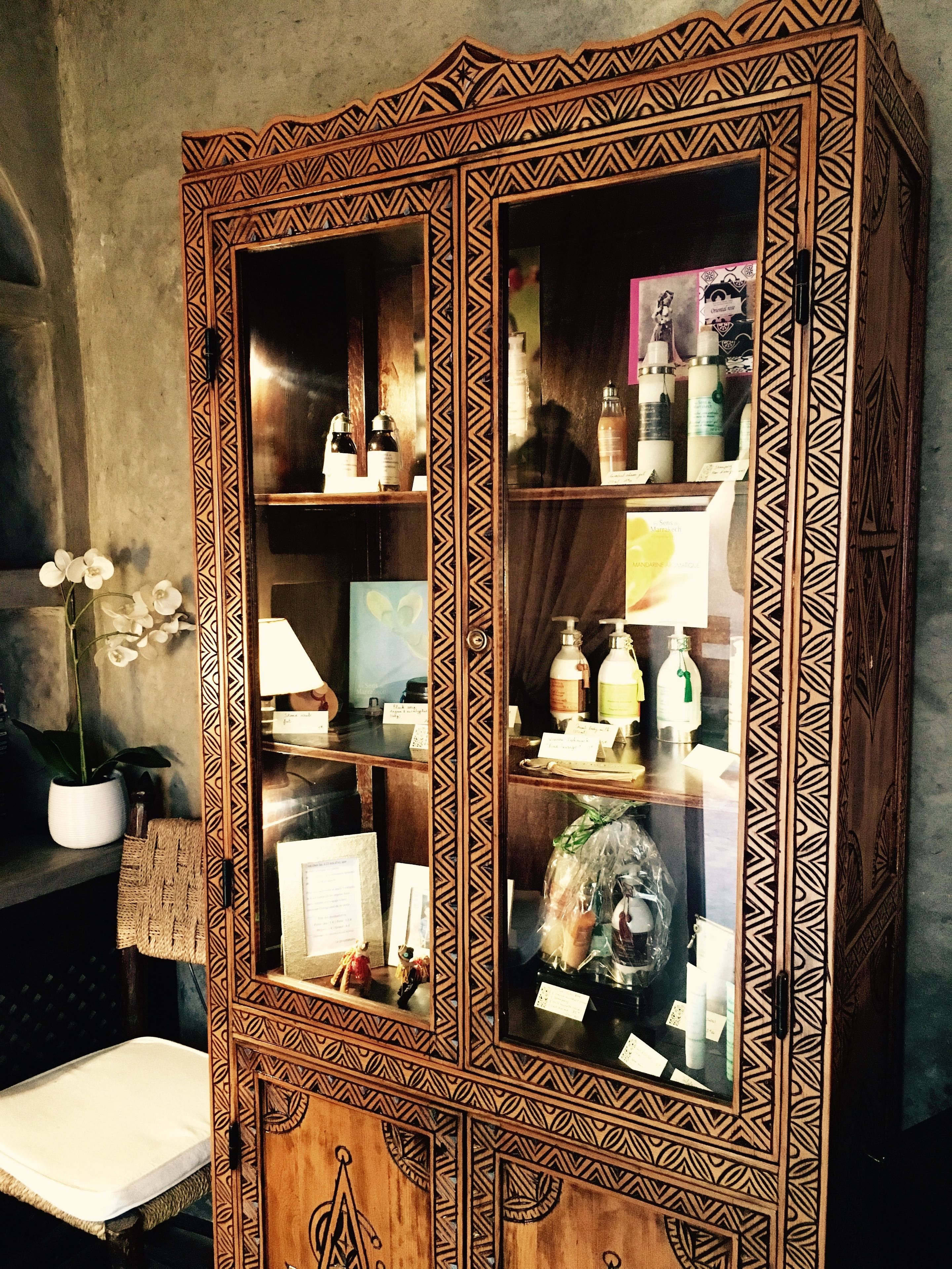 Un mueble de madera con elaborados grabados y puertas de cristal que exhiben diversos objetos.