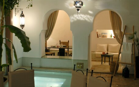 A pool area with lounge chairs, a dining area, and a sofa.