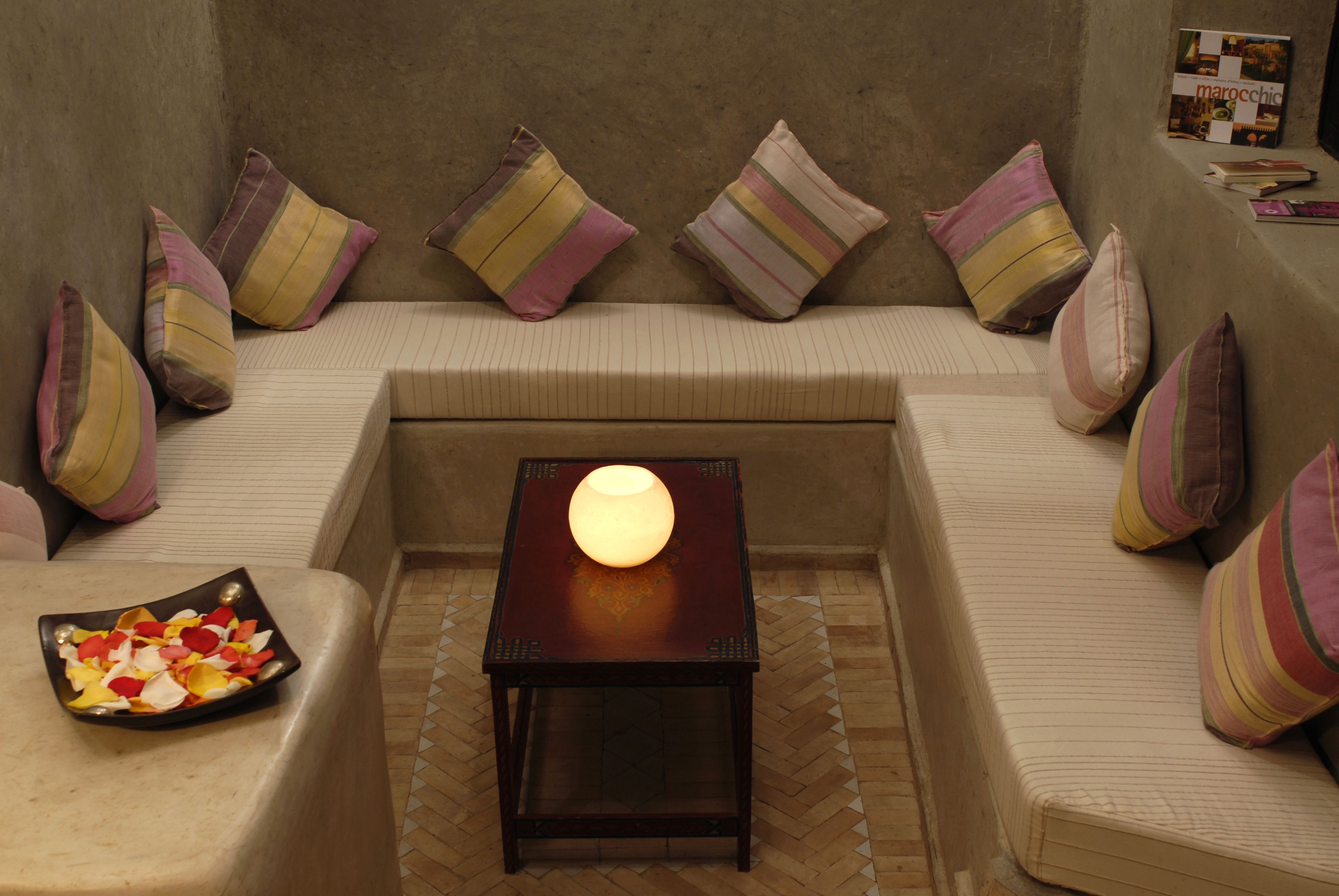 A cozy seating area with a cushioned sofa, striped pillows, a small table with a lamp, and a decorative bowl on the floor.