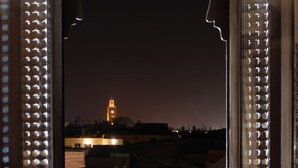 A bed with white pillows and a view of a tower through a window with decorative lights. - Riad Tawargit (Marrakech)
