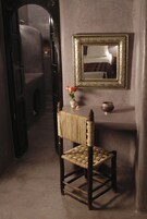 A rustic room with a woven chair, a mirror, and a vase with flowers.